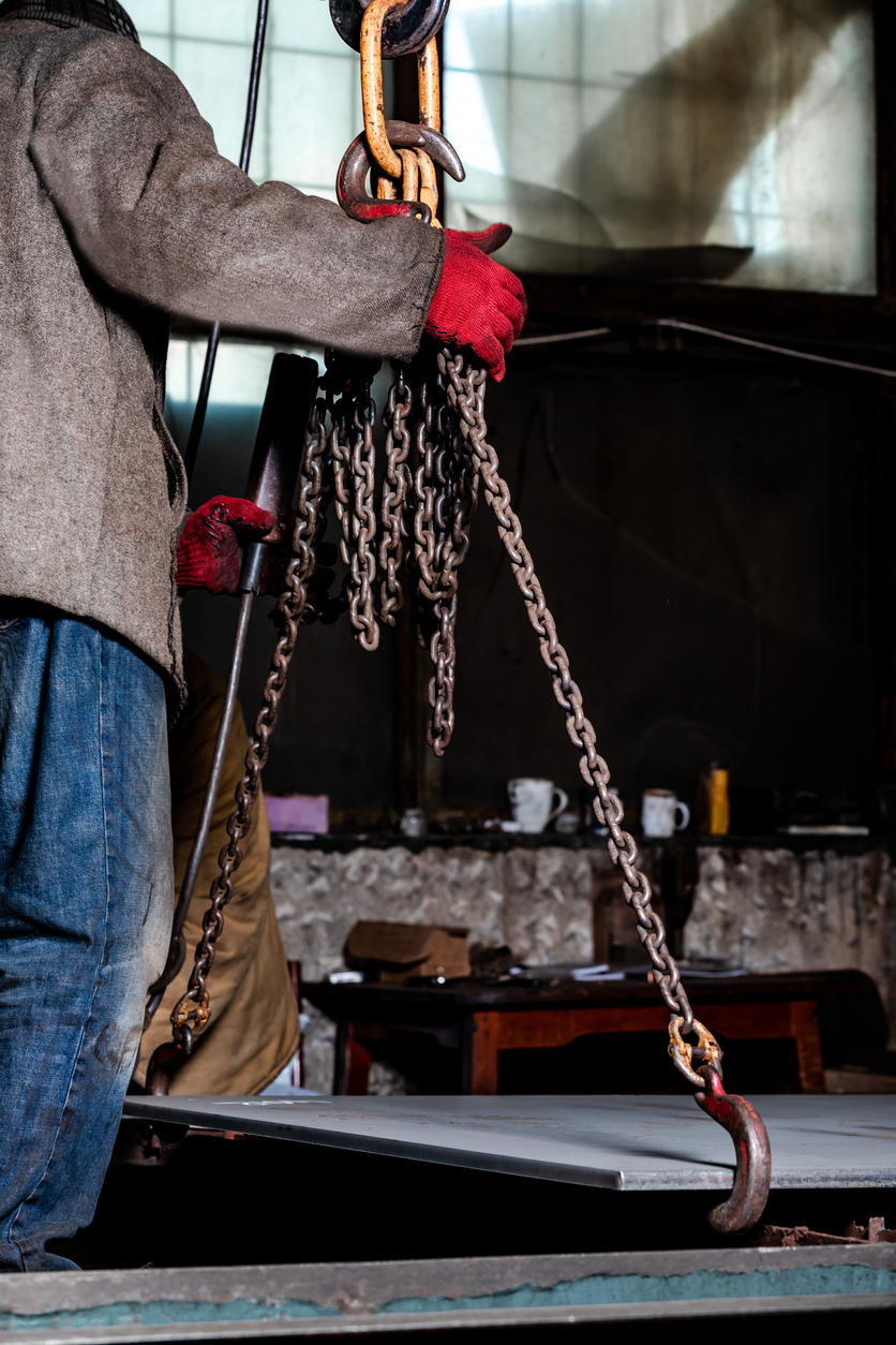 industry worker is working with hooks from crane .at a factory