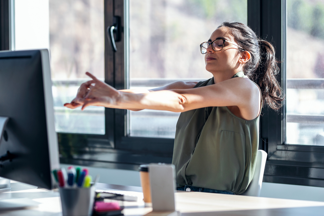 Tired businesswoman stretching body for relaxing while working with computer in the office.