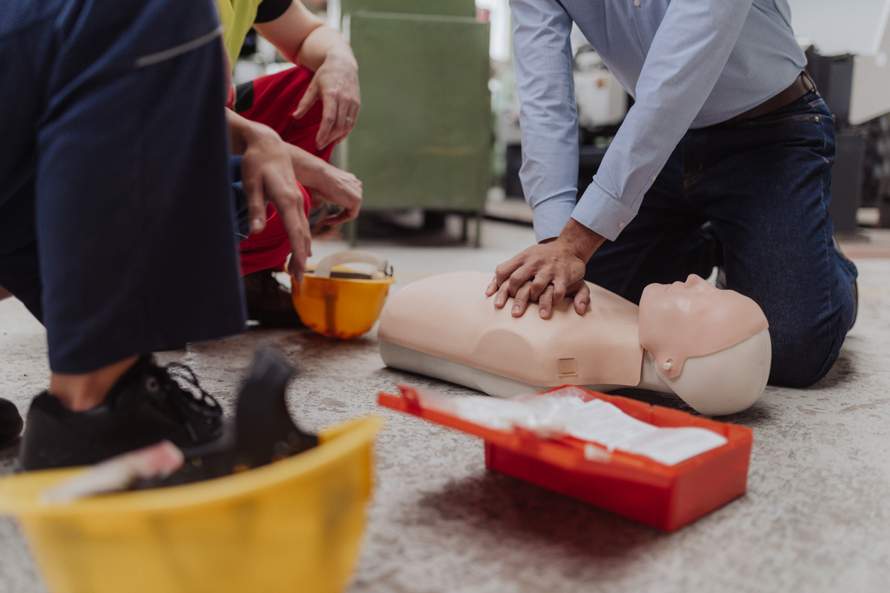 Male instructor showing first medical aid on doll during training course indoors, close up