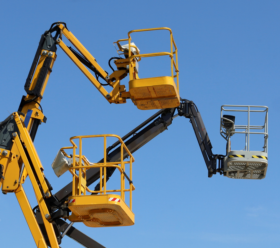 Three aerial working platforms of cherry picker, two yellow and one black, against blue sky.