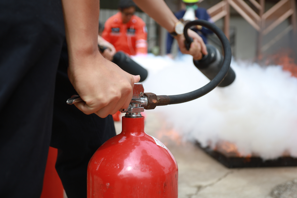 Employees firefighting training, Concept Employees hand using fire extinguisher fighting fire closeup