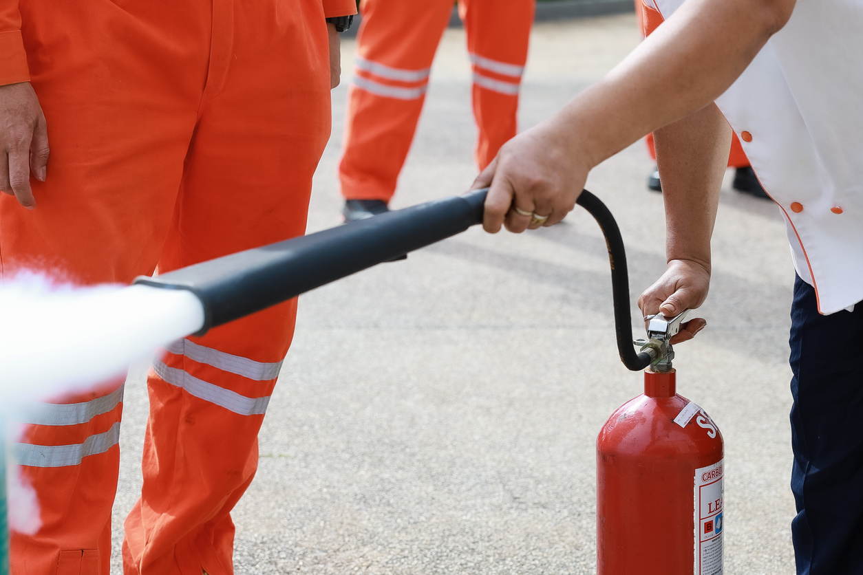 Employees firefighting training, Concept Employees hand using fire extinguisher fighting fire closeup. Spray fire extinguisher.