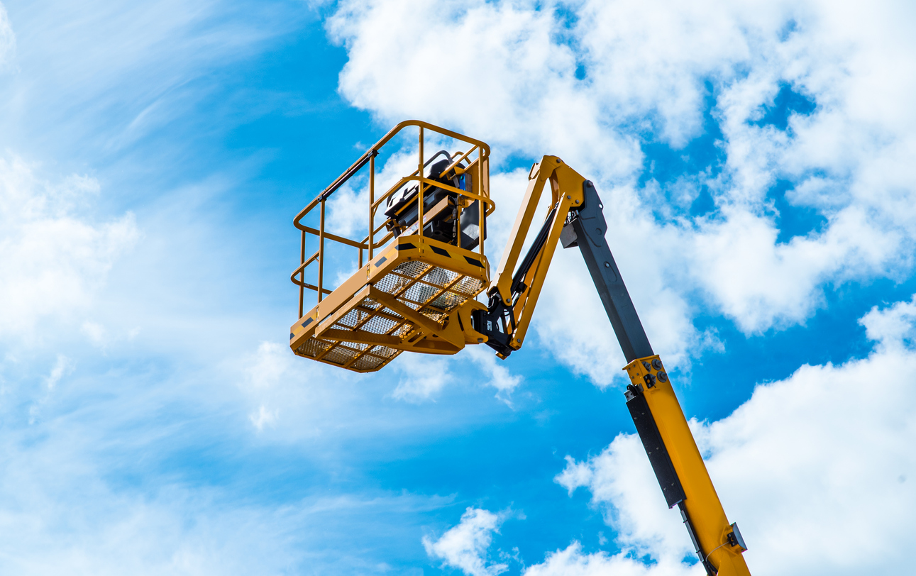 Hydraulic lift platform with bucket of yellow construction vehicle, heavy industry, blue sky and white clouds on background