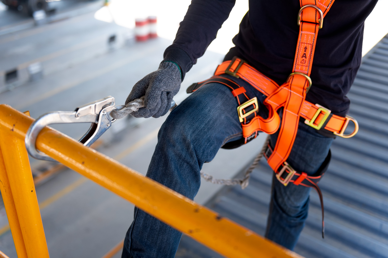 Construction worker use safety harness and safety line working on a new construction site project.